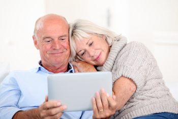 A mature couple watches their wedding video on a tablet
